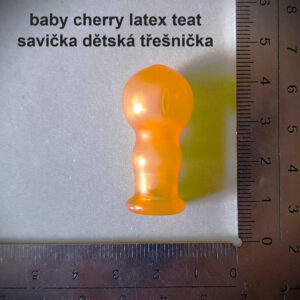 Dětská latexová savička ve tvaru třešně vedle pravítka.