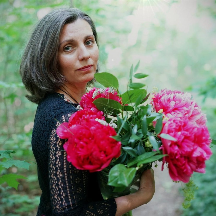 Marion Soňa Karausová – Dlaně plné ticha – portrait of a woman holding a bouquet of pink and red peonies in a garden.