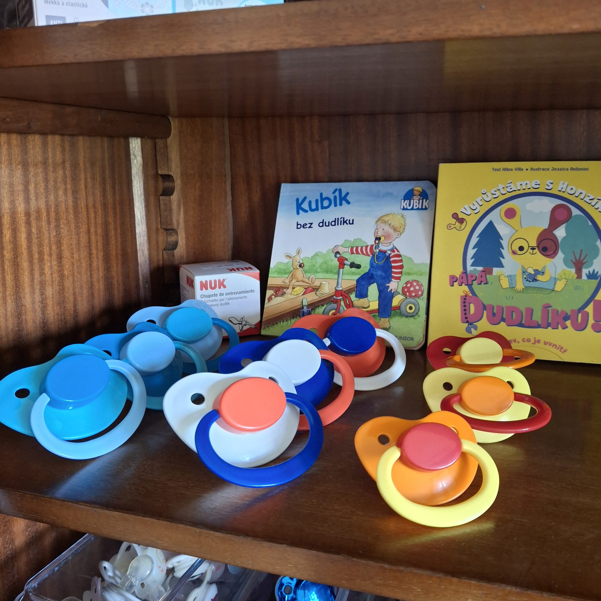 Colourful FIXX pacifiers in front of product boxes on a doodoo showroom shelf.