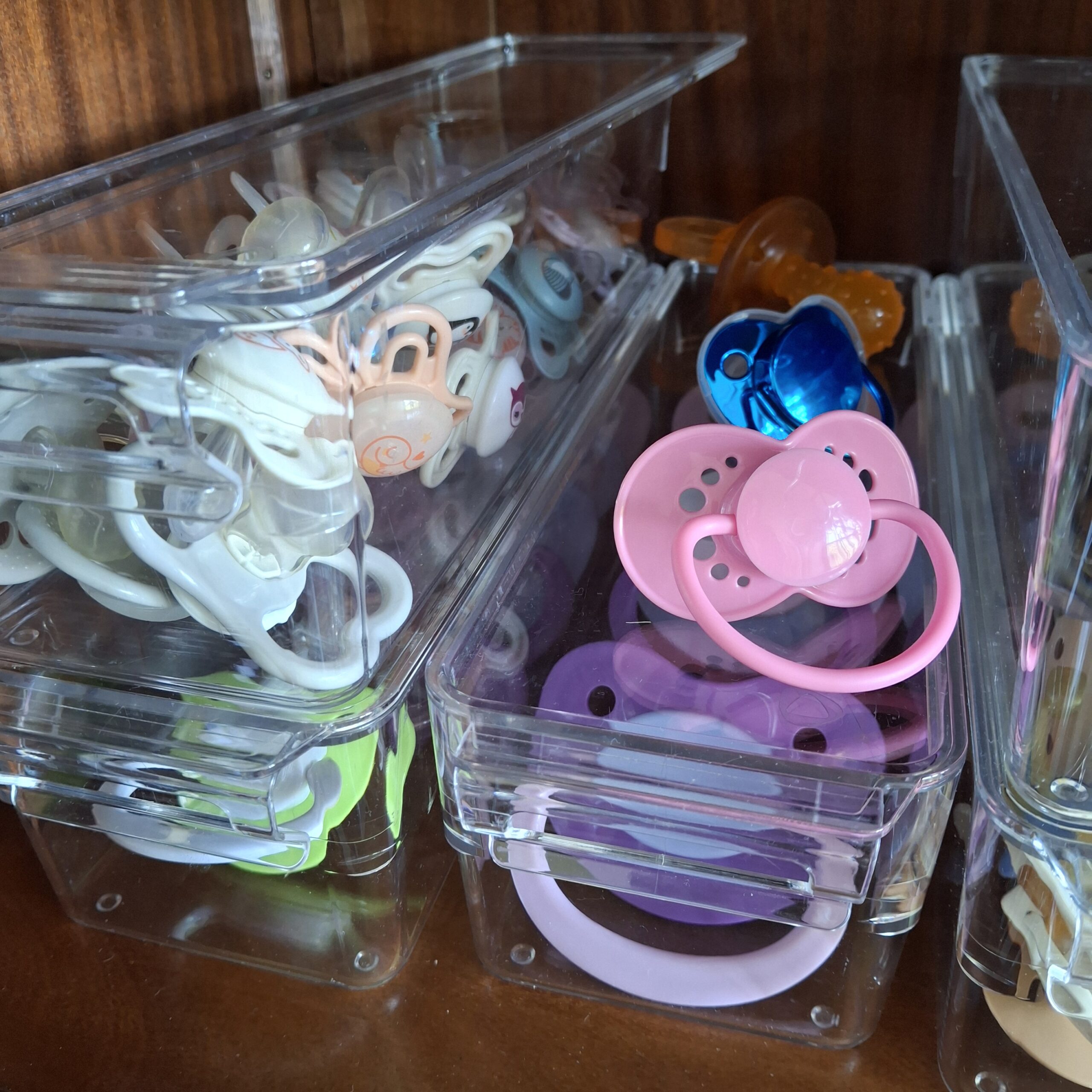 Pacifiers with white, pink and blue shields in clear organisers in the doodoo showroom.