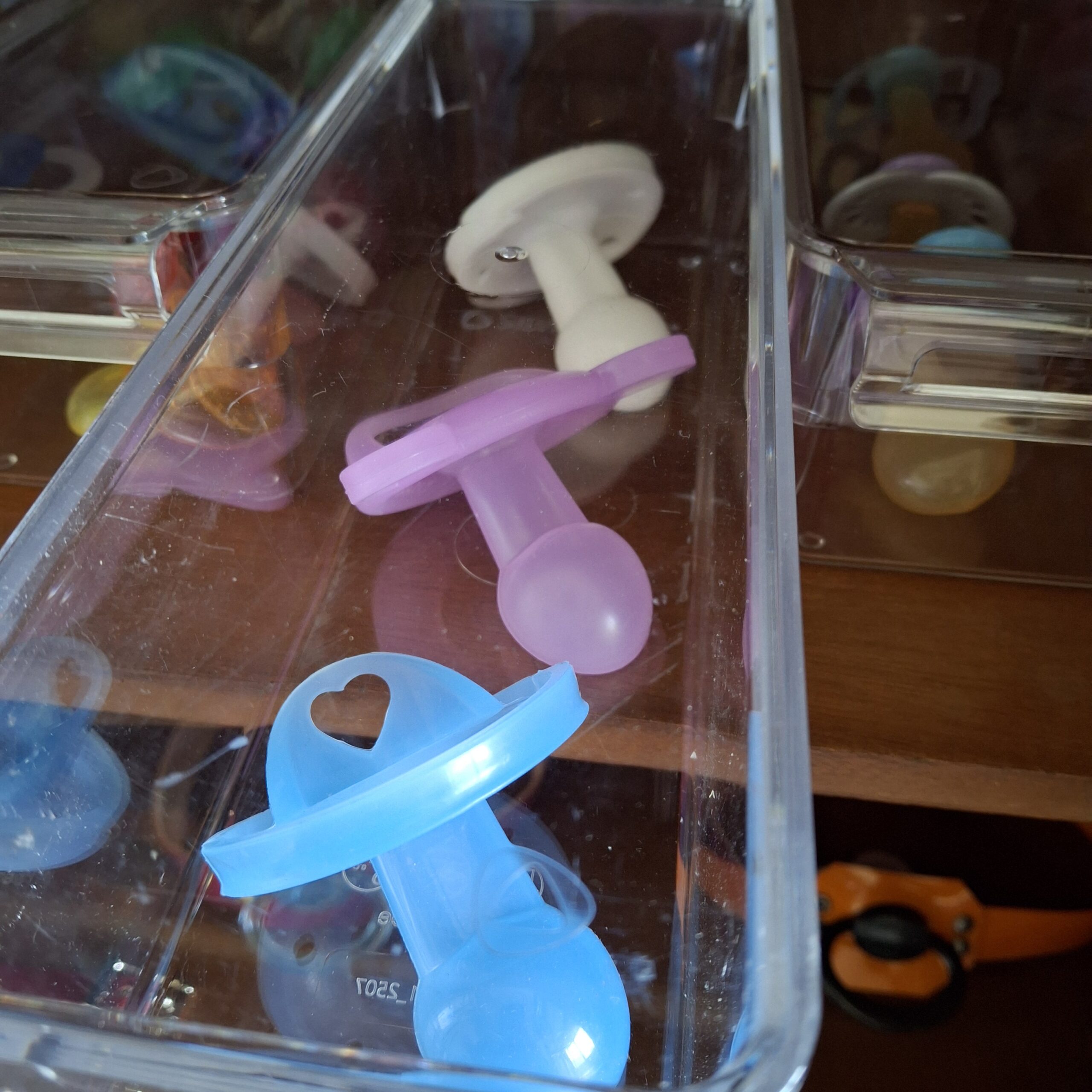 White, purple and blue silicone pacifiers in a doodoo showroom organiser.